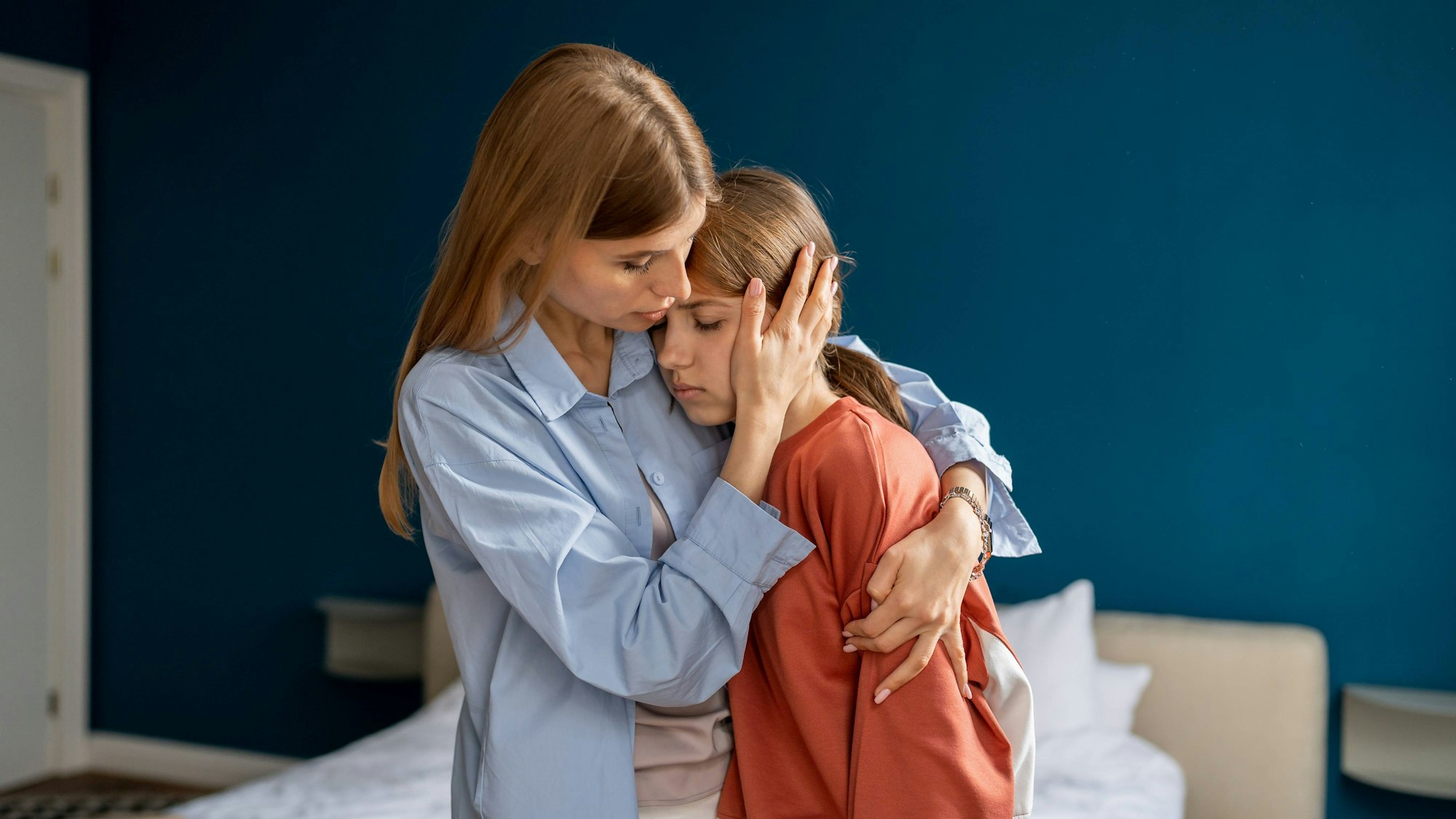 Eine Mutter nimmt ihre Teenager-Tochter in den Arm