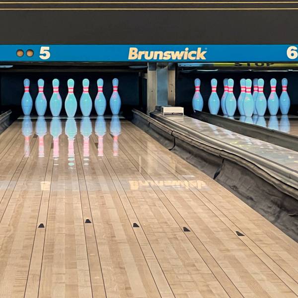 Pins stehen sortiert auf einer Bowling-Bahn.