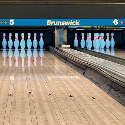 Pins stehen sortiert auf einer Bowling-Bahn.