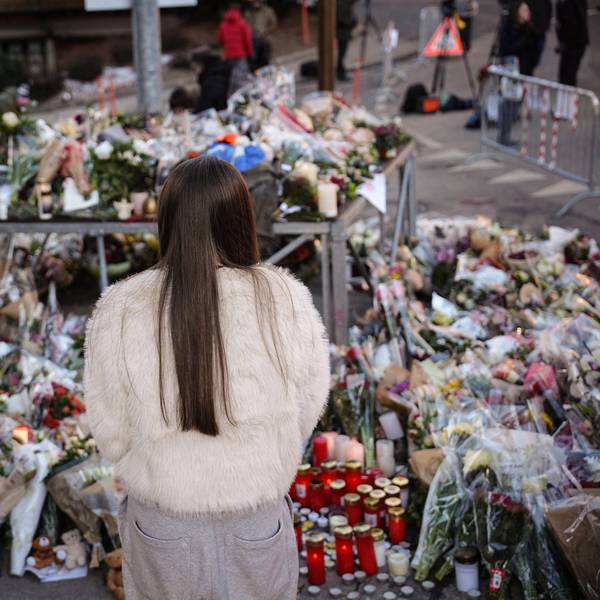 Eine junge Frau steht vor Blumen in Crans-Montana. Unter den Opfern der Brandkatastrophe sind auch Teenager.
