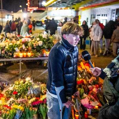 Ein junger Überlebender der Feuerkatastrophe spricht vor einem Blumenmeer in Crans-Montana mit Journalisten.