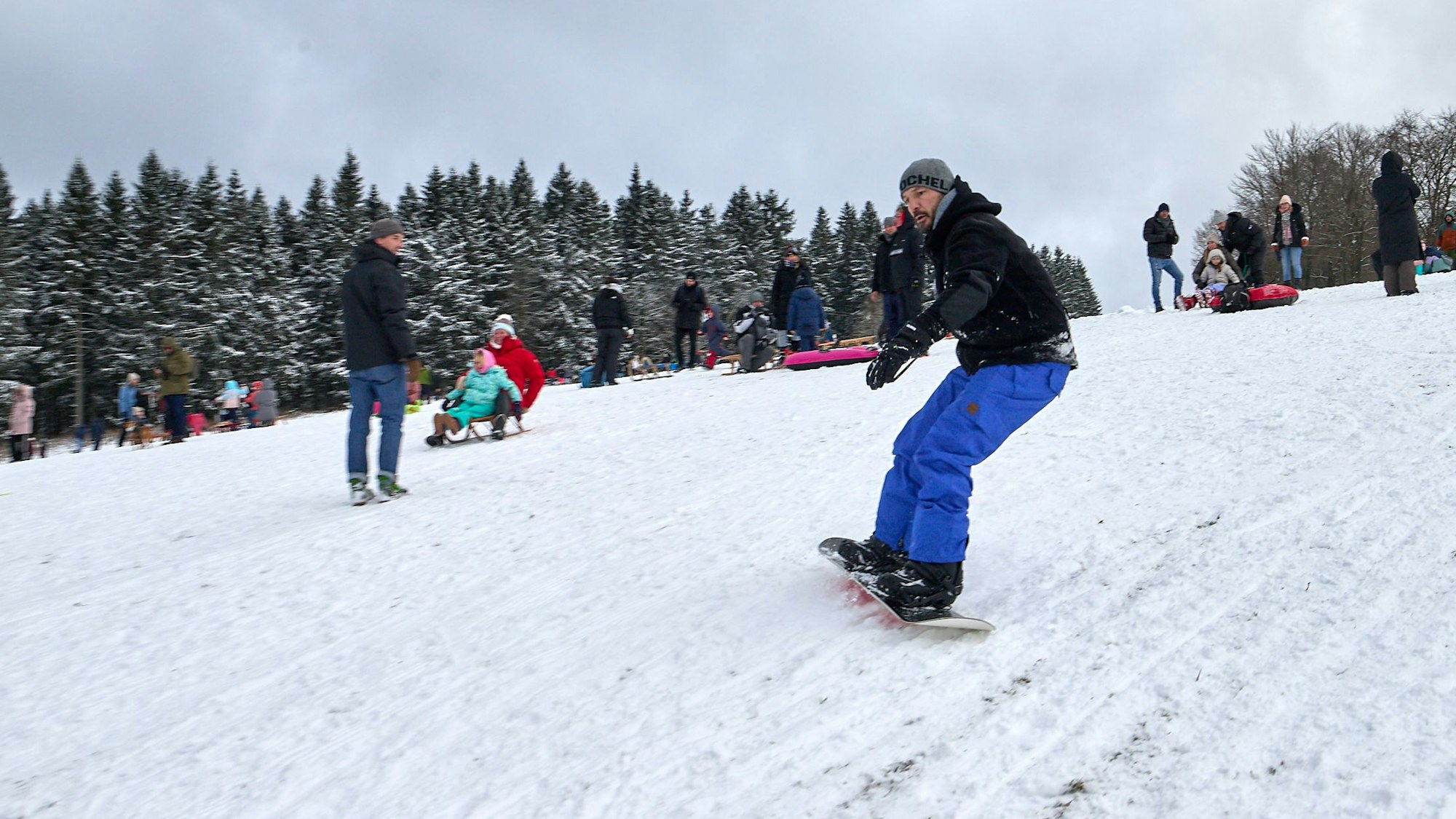 Ein Mann fährt auf einem Snowboard einen Hang hinunter.