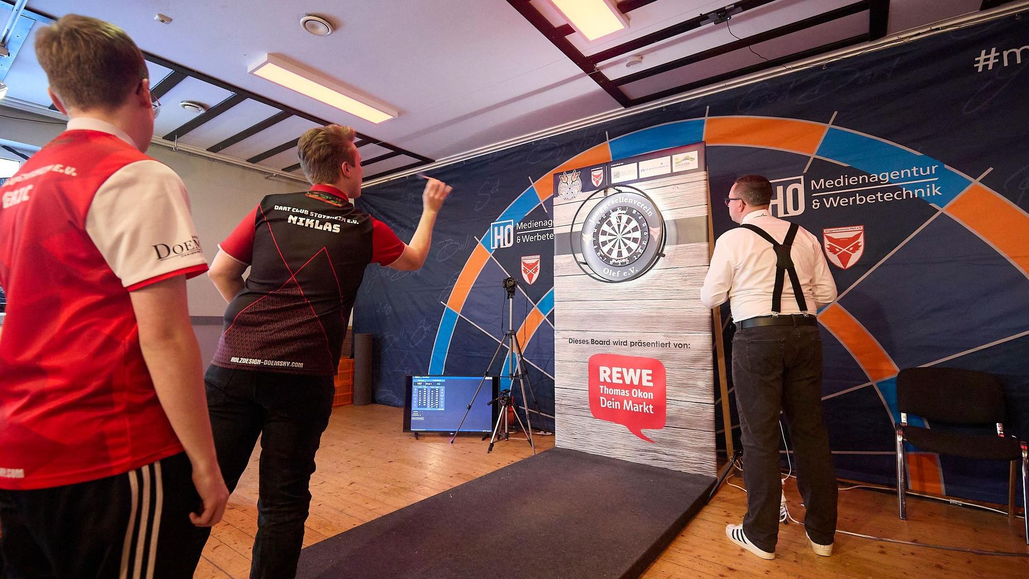 Das Bild zeigt einen Darter beim Werfen der Pfeile.