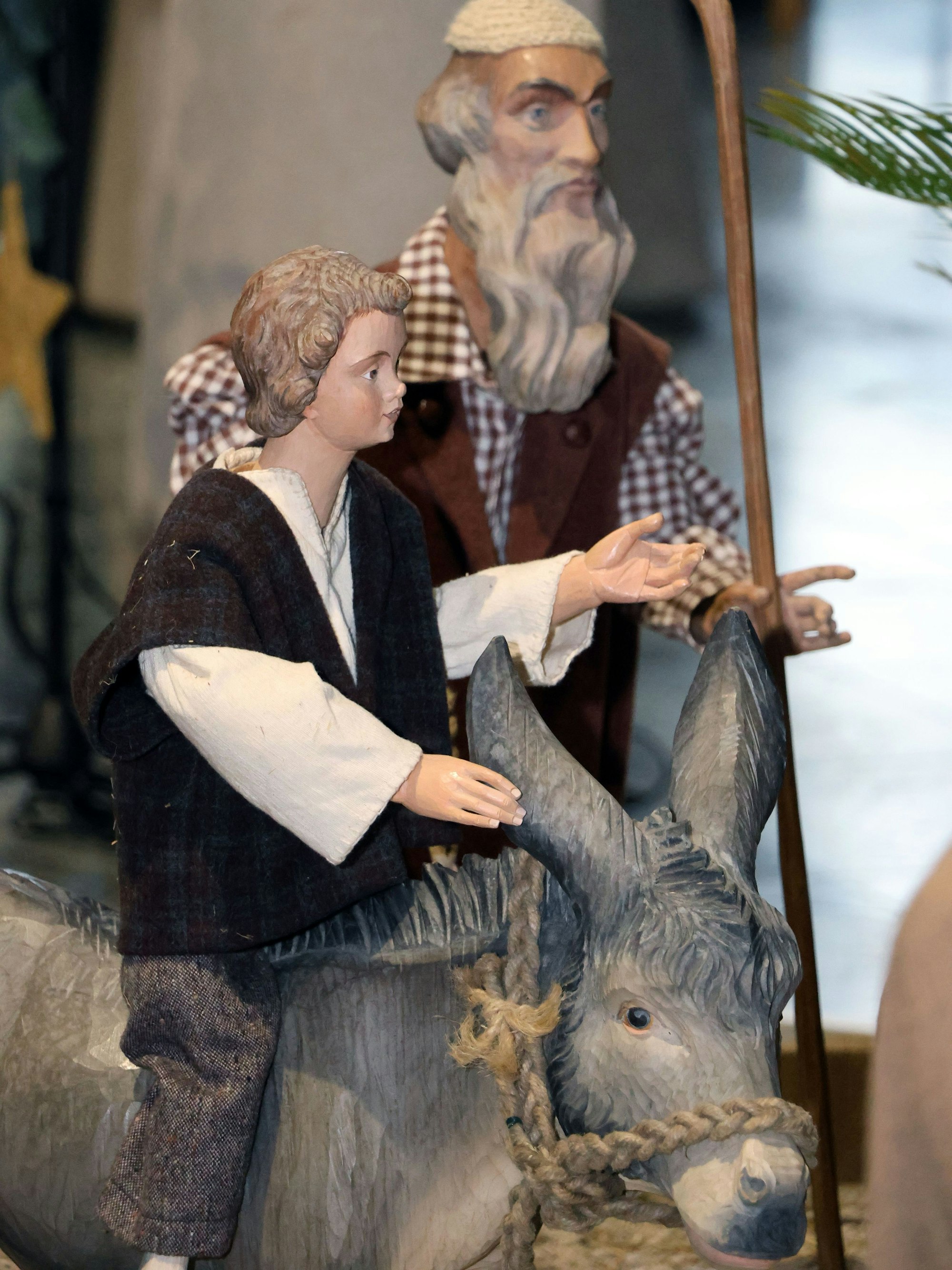 Auf dem Bild sind zwei Krippenfiguren und ein Holzesel zu sehen.