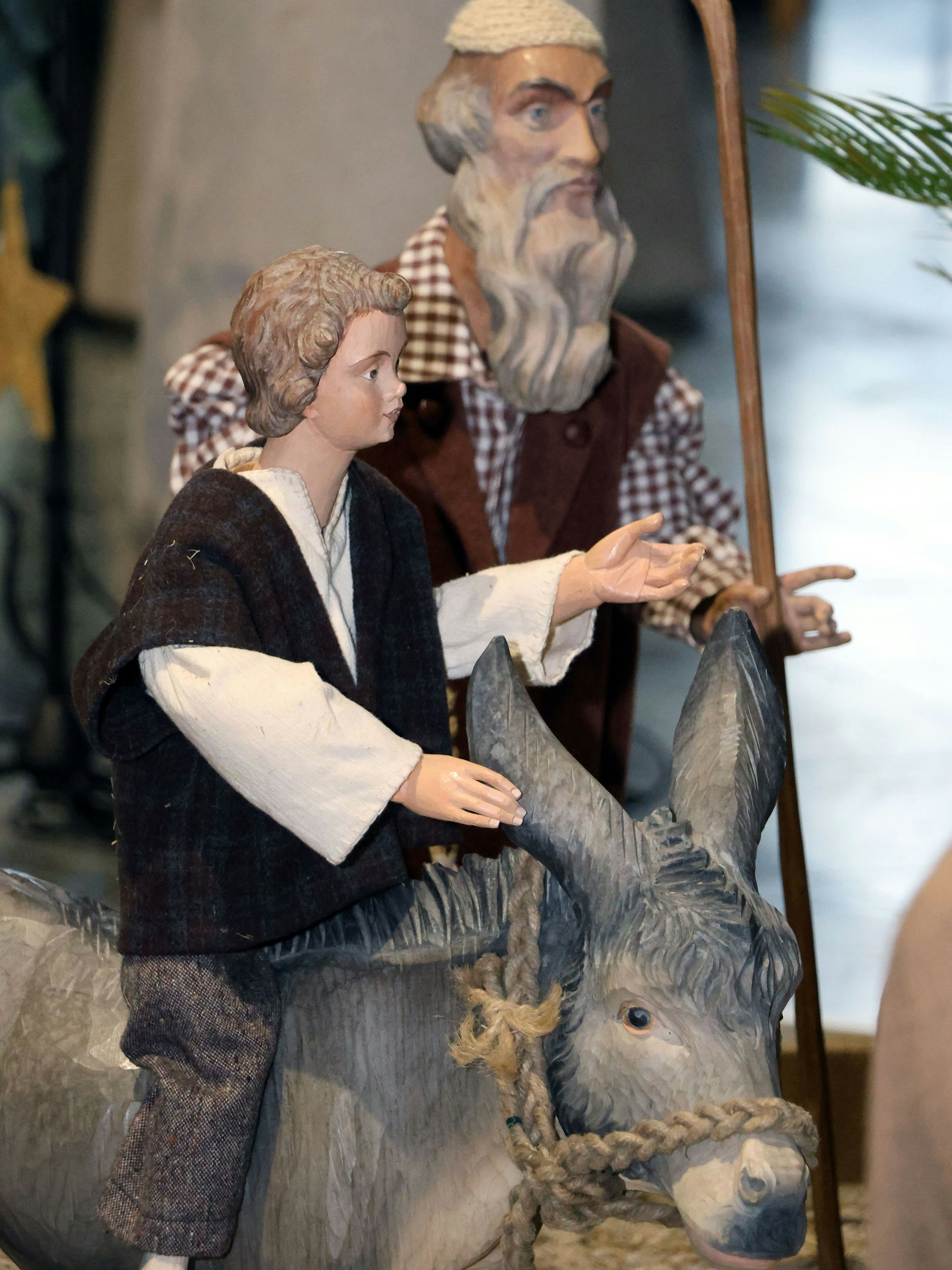 Auf dem Bild sind zwei Krippenfiguren und ein Holzesel zu sehen.