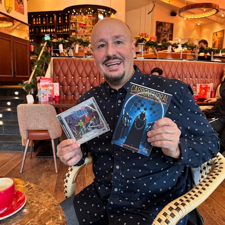 Ein Mann hält ein Buch und eine CD in seinen Händen.