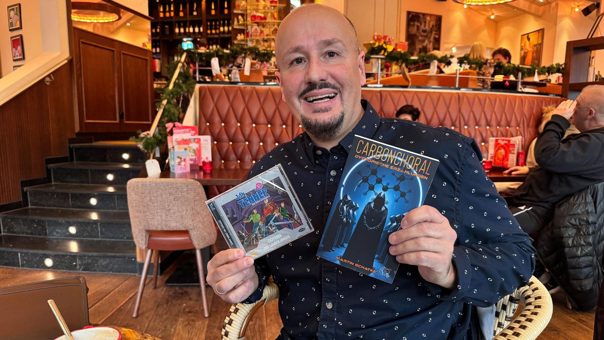 Ein Mann hält ein Buch und eine CD in seinen Händen.