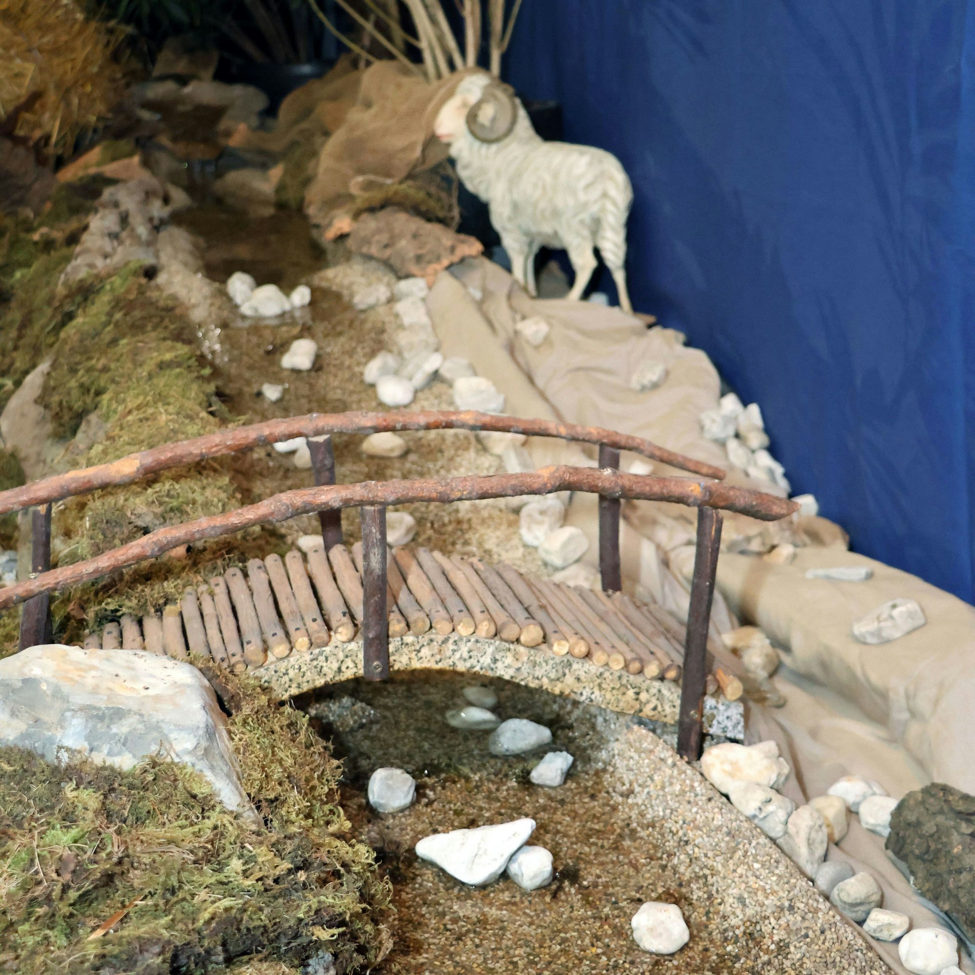 Auf dem Bild ist ein künstlicher Fluss mit einer Holzbrücke zu sehen.