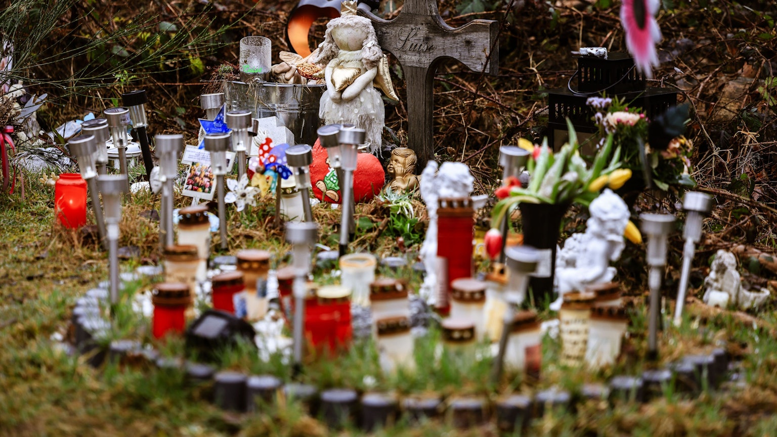 Kerzen, Blumen und Figuren liegen am Fundort an der Landesgrenze zwischen Rheinland-Pfalz und Nordrhein-Westfalen. Foto: Oliver Berg/dpa