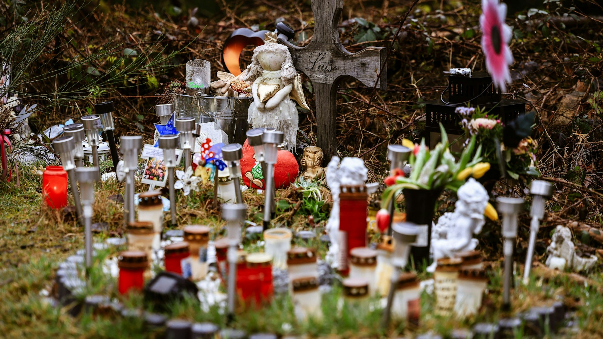 Kerzen, Blumen und Figuren liegen am Fundort an der Landesgrenze zwischen Rheinland-Pfalz und Nordrhein-Westfalen. Foto: Oliver Berg/dpa