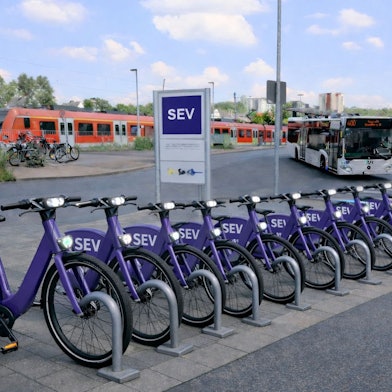 Fahrräder mit violetter Lackierung und der Aufschrift „SEV S-Bahnlinie 11“ stehen vor dem Bergisch Gladbacher S-Bahnhof.