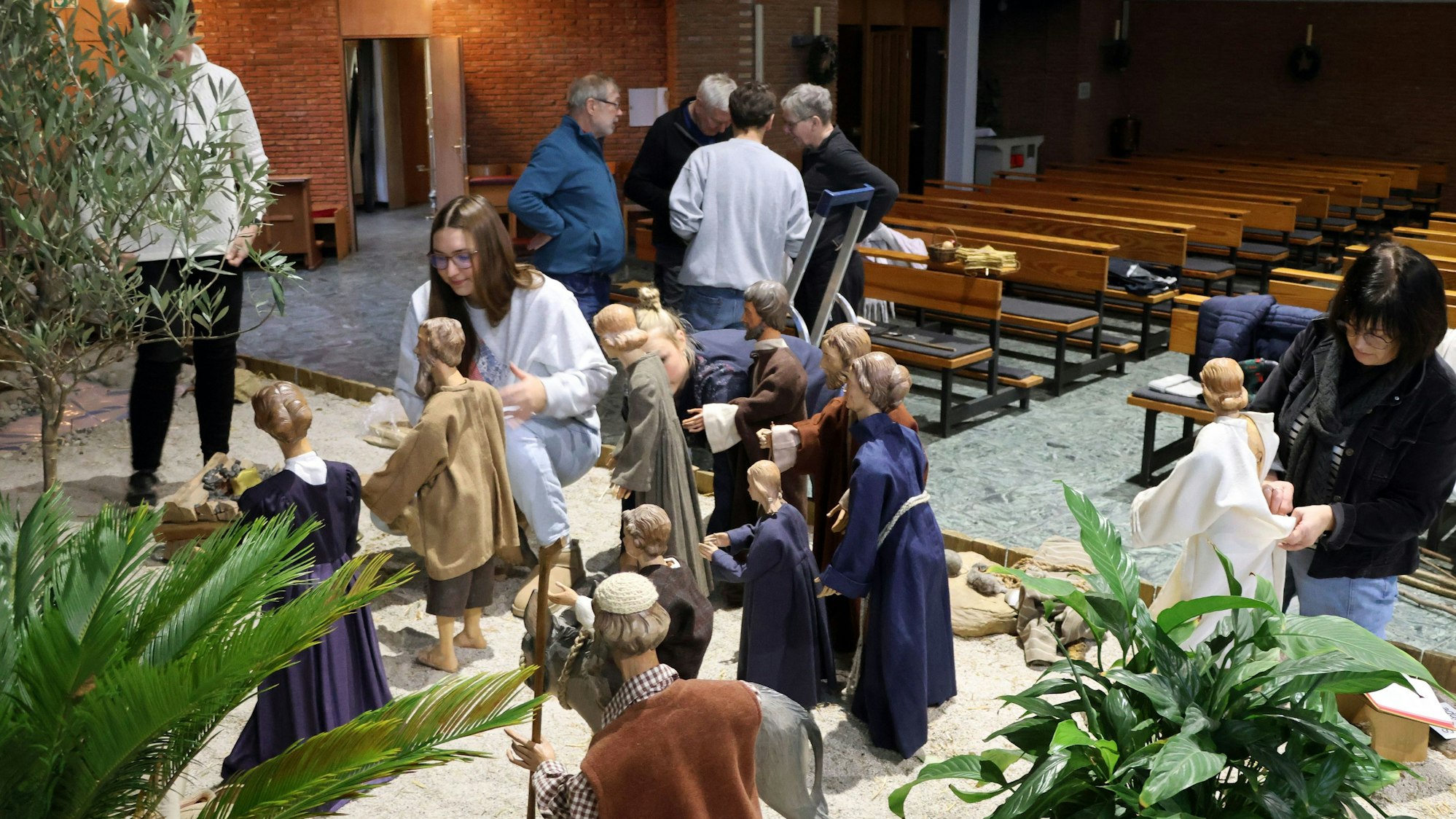 Auf dem Bild sind Ehrenamtler zu sehen, die in einer Kirche eine Krippe aufbauen.