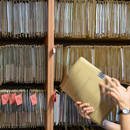Eine Person ordnet eine Akte in einen Schrank.