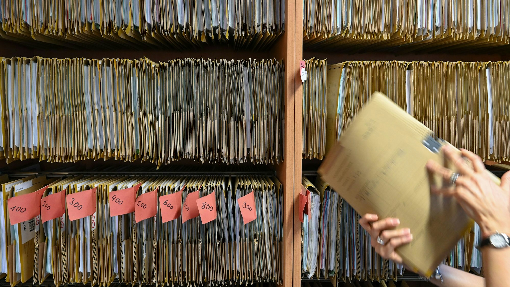 Eine Person ordnet eine Akte in einen Schrank.