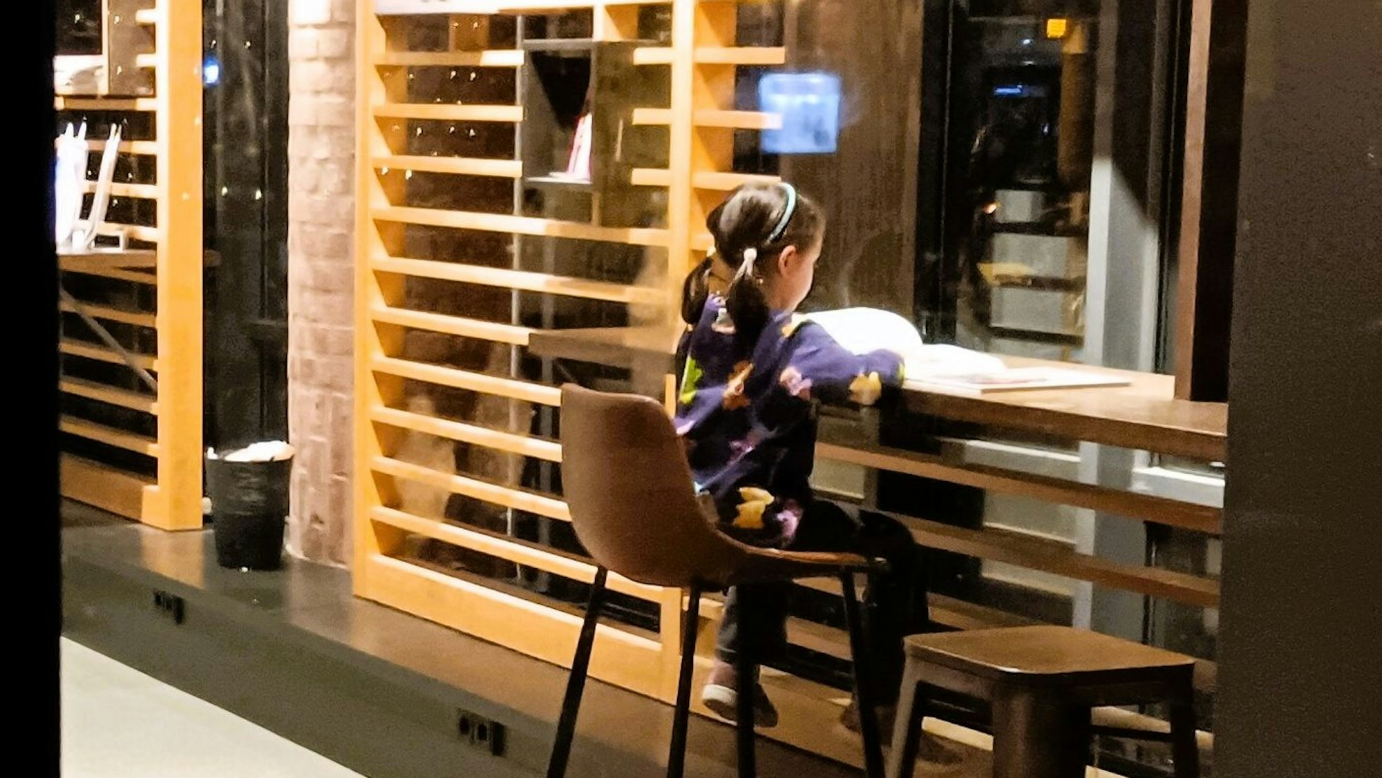 Ein junges Mädchen liest an einem Tisch in einer modernen Bibliothek.