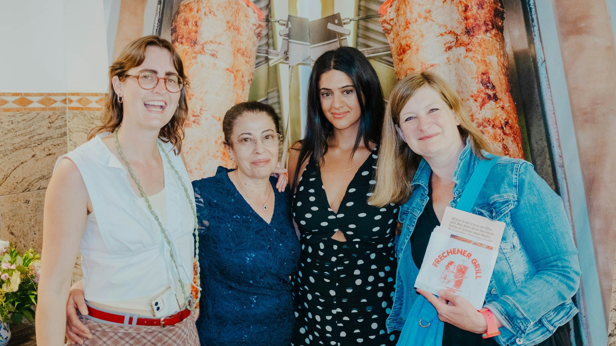 Auf dem Bild sind vier Frauen vor einem großen Foto eines Döner-Spießes zu sehen.