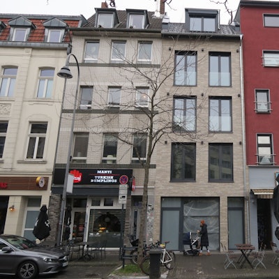 Eine Reihe Häuser an einer belebten Straße: Das Haus in der Mitte steht leer.