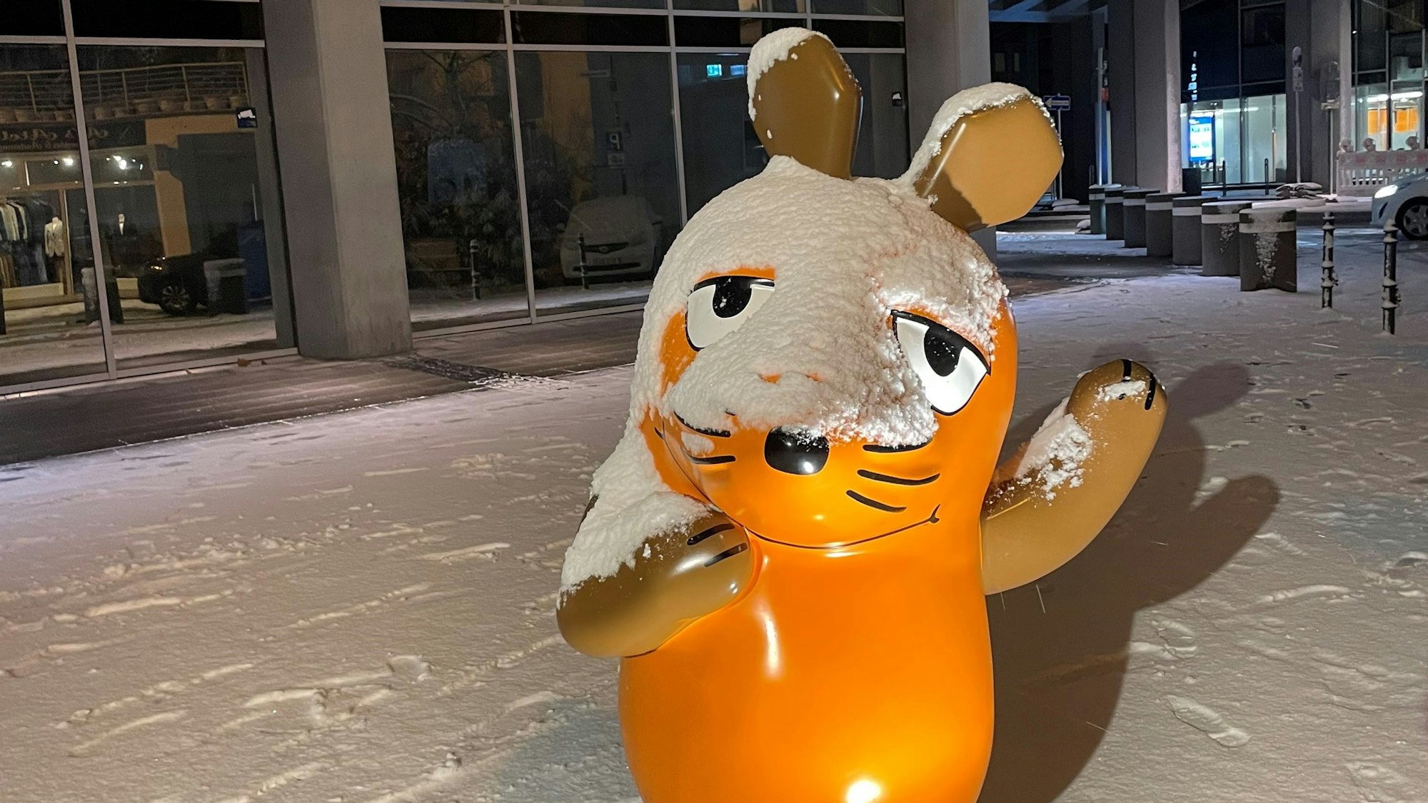 Die Maus steht mit Schnee bedeckt vor dem WDR-Gebäude.