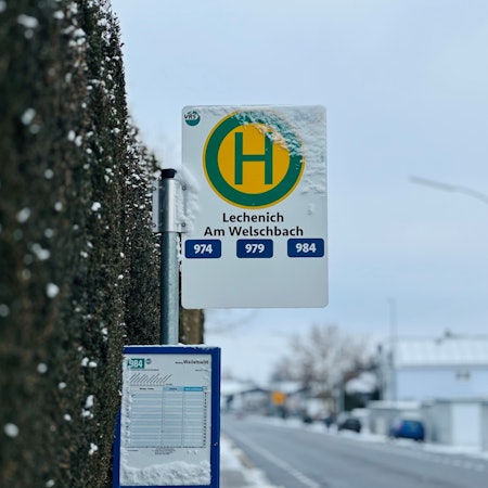 Zu sehen ist ein Haltestellenschild an einer Straße.