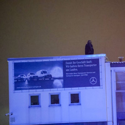 Eine Person befindet sich im Dunkeln auf dem Dach eines Gebäudes.