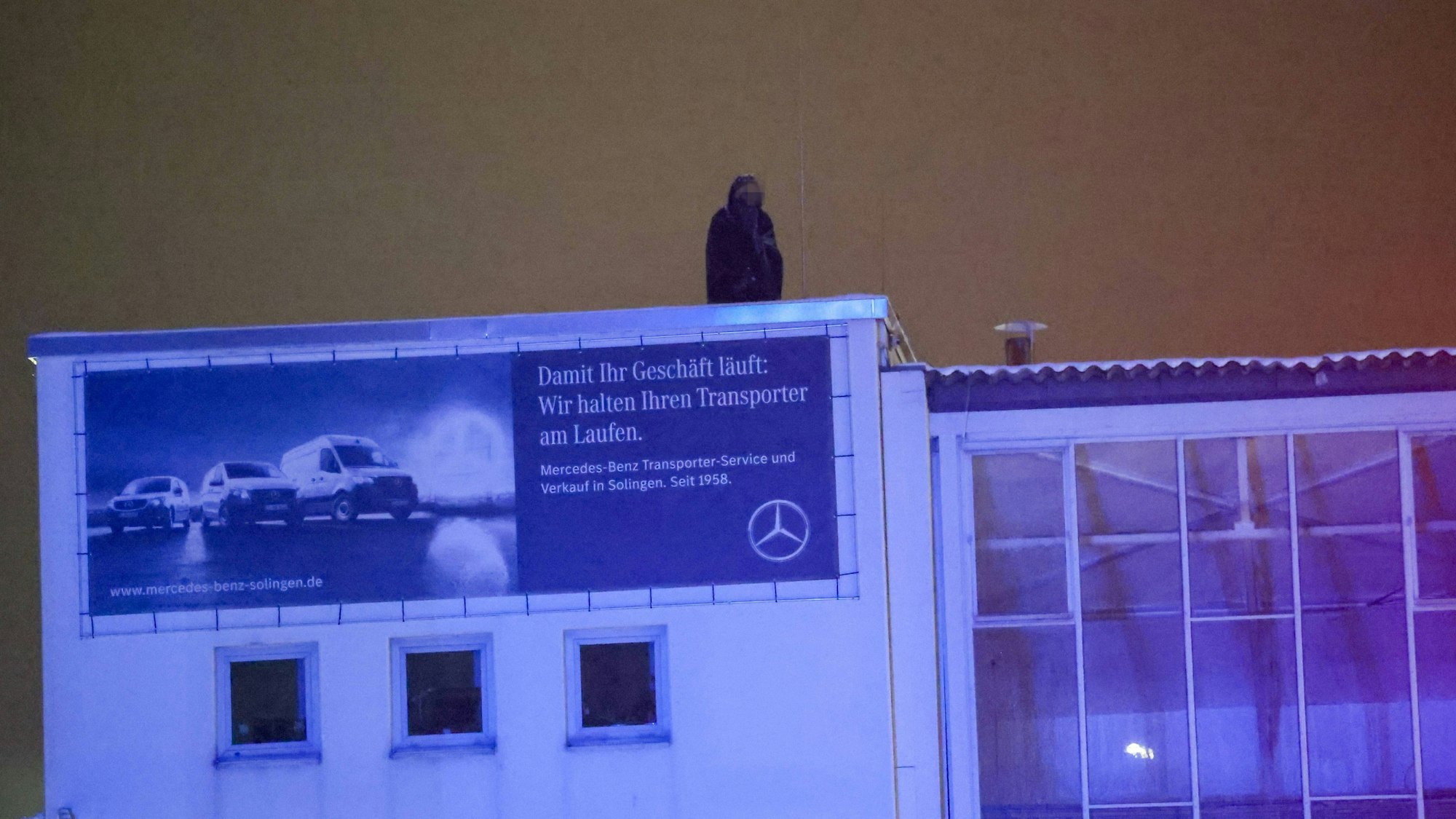 Eine Person befindet sich im Dunkeln auf dem Dach eines Gebäudes.