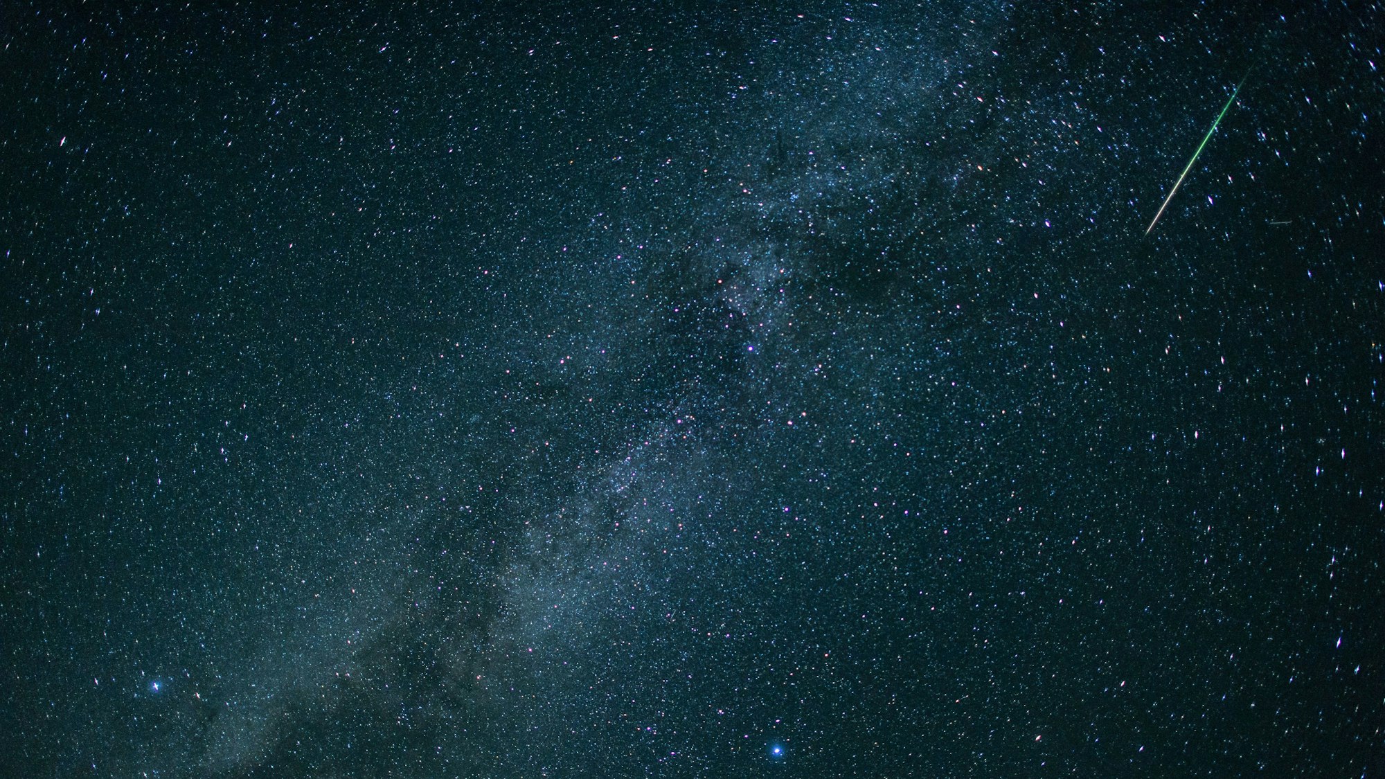 Eine Sternschnuppe leuchtet neben der Milchstraße am Himmel. (Symbolfoto)