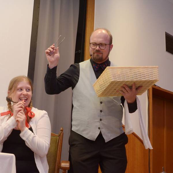 Magdalena Bork sitzt am Tisch, Gregor Weichsel steht in der Rolle des Butlers neben ihr.