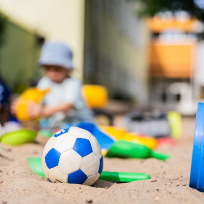 Ein Kind spielt im Sandkasten einer Kita.