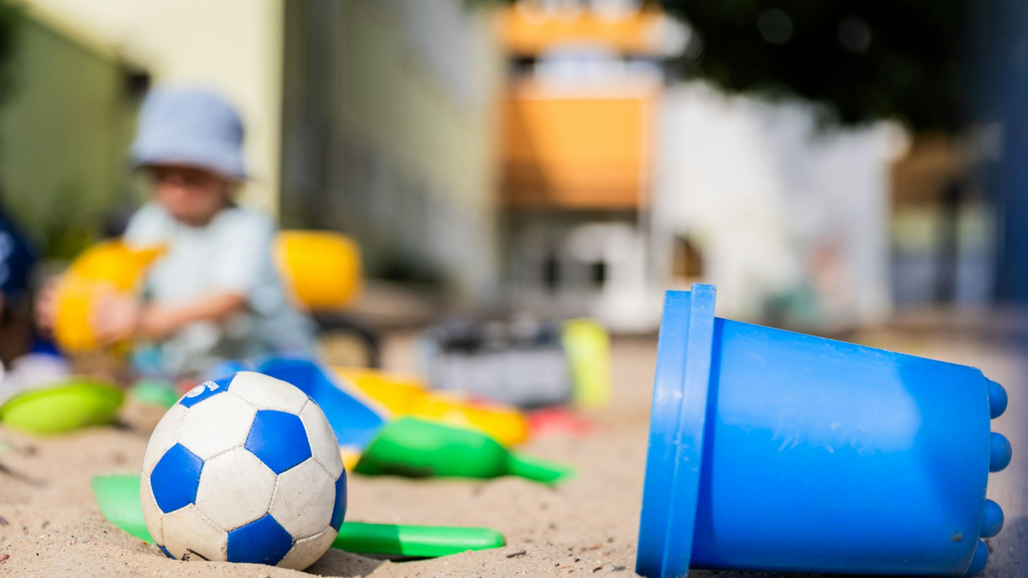 Ein Kind spielt im Sandkasten einer Kita.