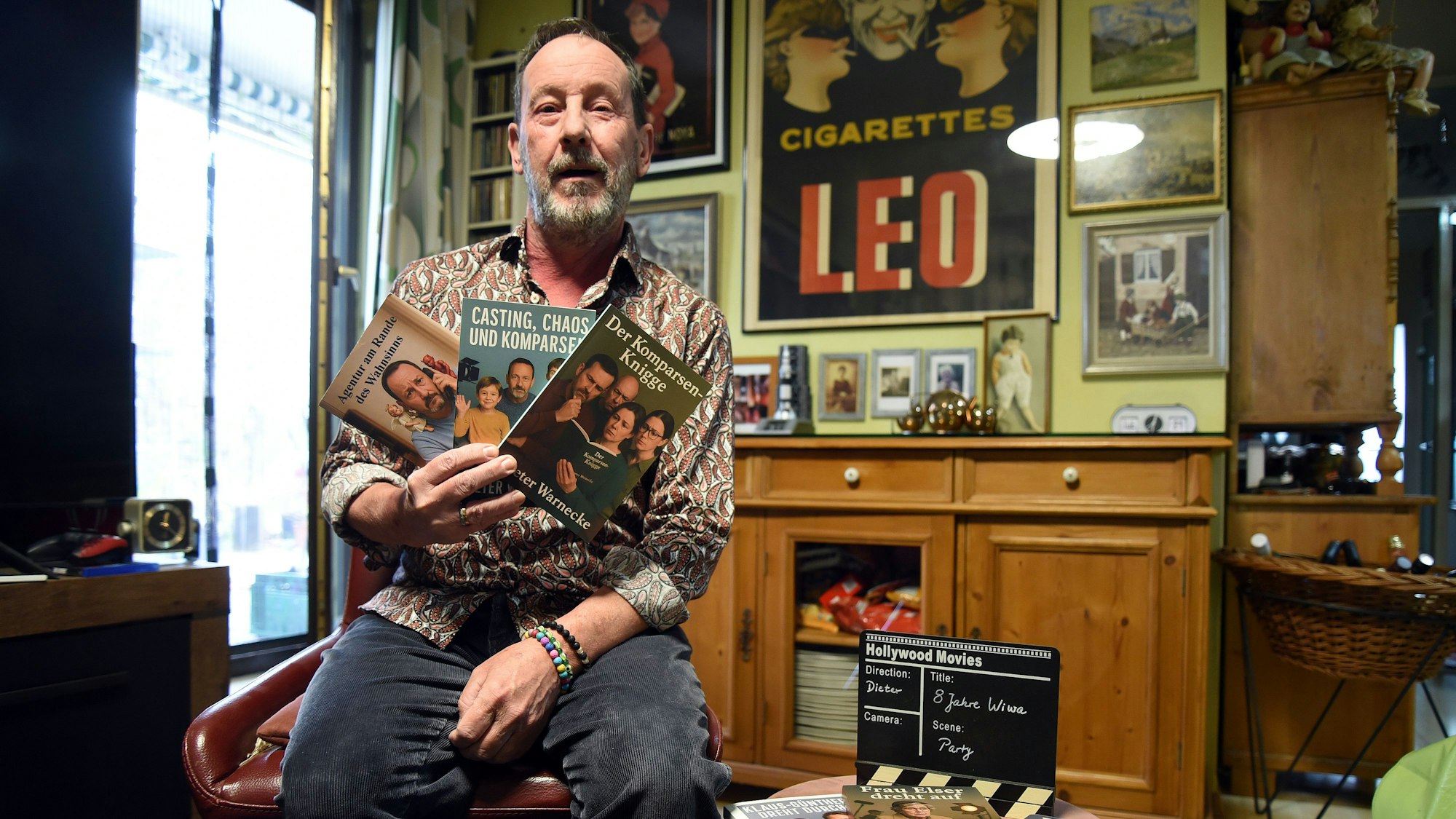 Ein Mann hält drei Bücher in die Kamera.