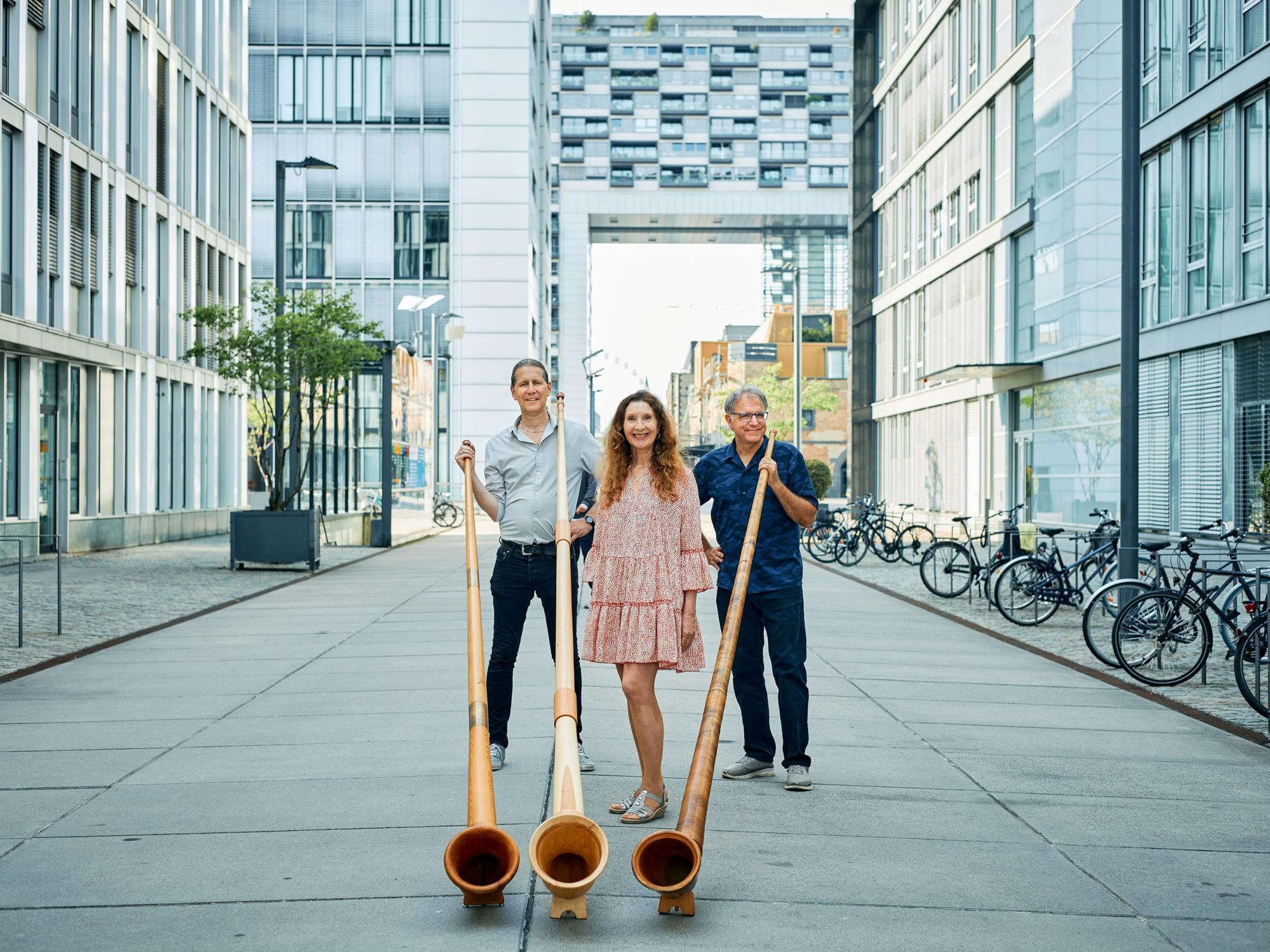 Zwei Musiker und eine Musikerin mit drei Alphörnern.