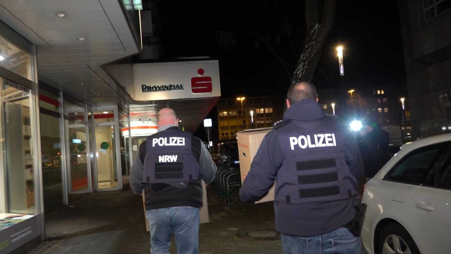 06.01.2026, Nordrhein-Westfalen, Gelsenkirchen: Einsatzkräfte der Polizei verlassen nach der Durchsuchung die Sparkassenfiliale mit Beweismaterial. Nach dem spektakulären Bank-Einbruch in Gelsenkirchen versuchen Ermittler weiter einen Überblick über den Schaden und das Vorgehen der Täter zu bekommen. Foto: Markus Gayk/dpa +++ dpa-Bildfunk +++