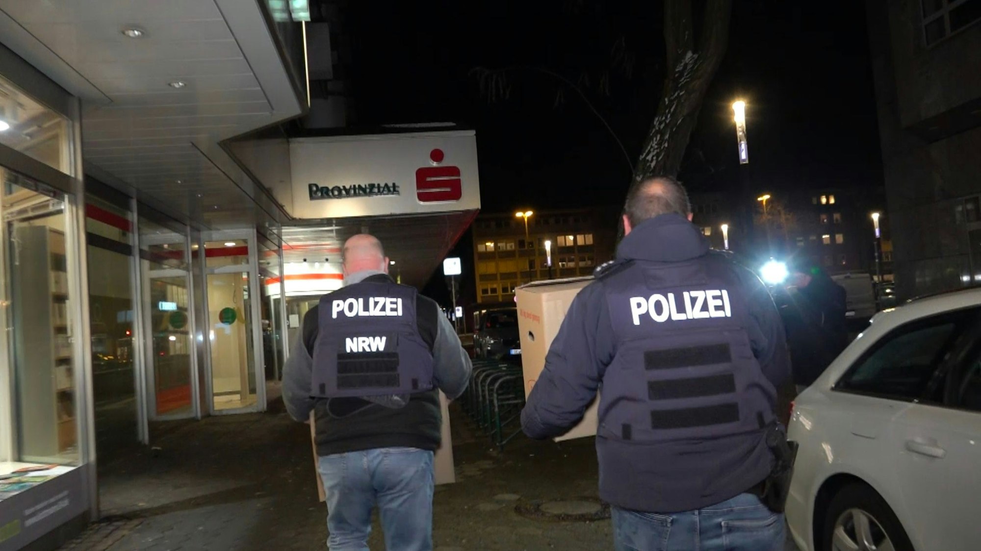 06.01.2026, Nordrhein-Westfalen, Gelsenkirchen: Einsatzkräfte der Polizei verlassen nach der Durchsuchung die Sparkassenfiliale mit Beweismaterial. Nach dem spektakulären Bank-Einbruch in Gelsenkirchen versuchen Ermittler weiter einen Überblick über den Schaden und das Vorgehen der Täter zu bekommen. Foto: Markus Gayk/dpa +++ dpa-Bildfunk +++