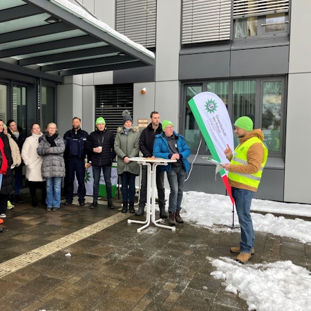 Eine Gruppe, darunter Gewerkschafter, steht vor dem Polizeigebäude in Gummersbach.
