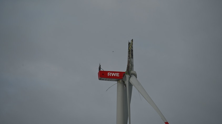 Das Bild zeigt die beschädigte Windkraftanlage. Eines der Rotorenblätter ist nach unten abgeknickt. Auf der Anlage ist der Schriftzug „RWE“ zu sehen.