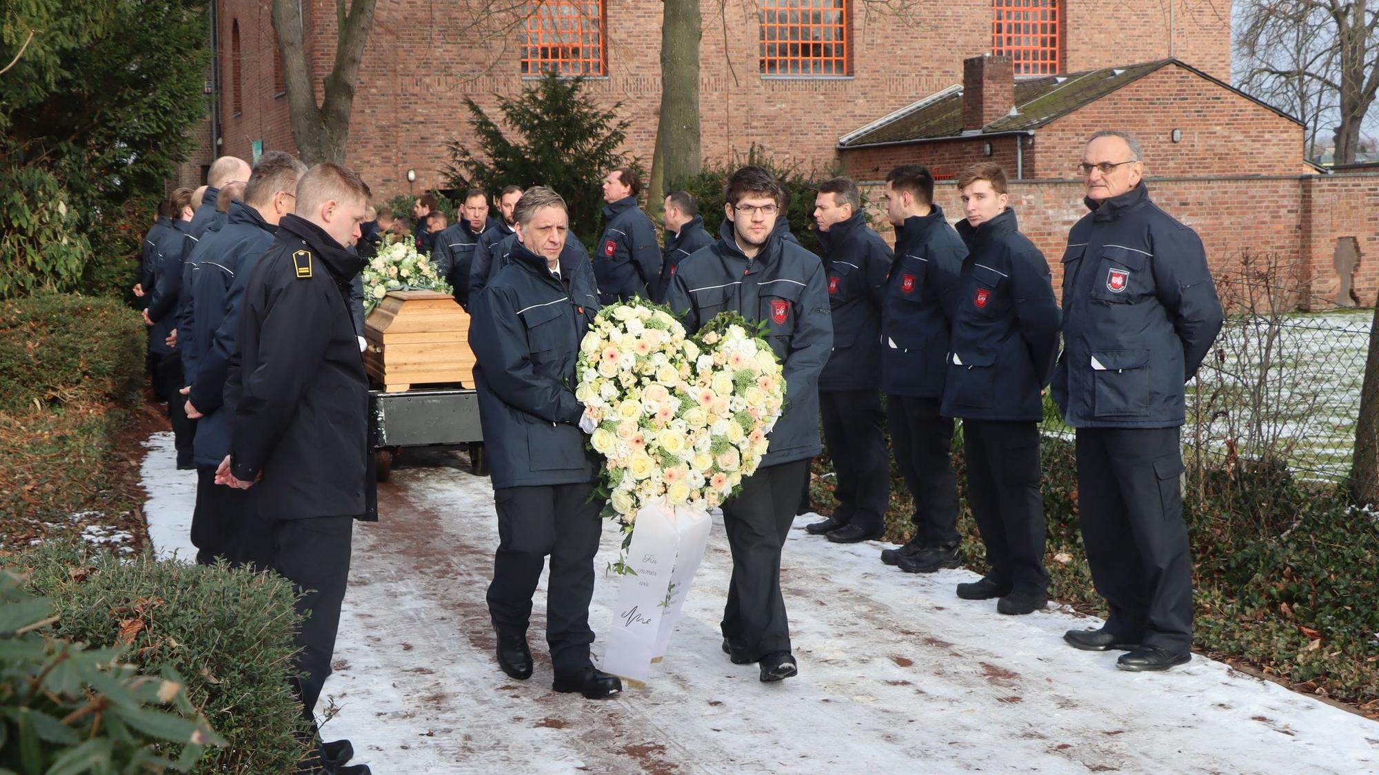 Feuerwehrleute standen Spalier, durch ihre Mitte tragen weitere Feuerwehrleute Blumen und einen Sarg.