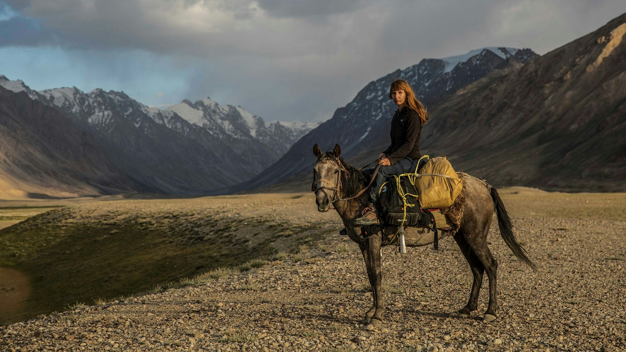 Priska Seisenbacher auf dem Rücken eines Pferdes im Gebirge.
