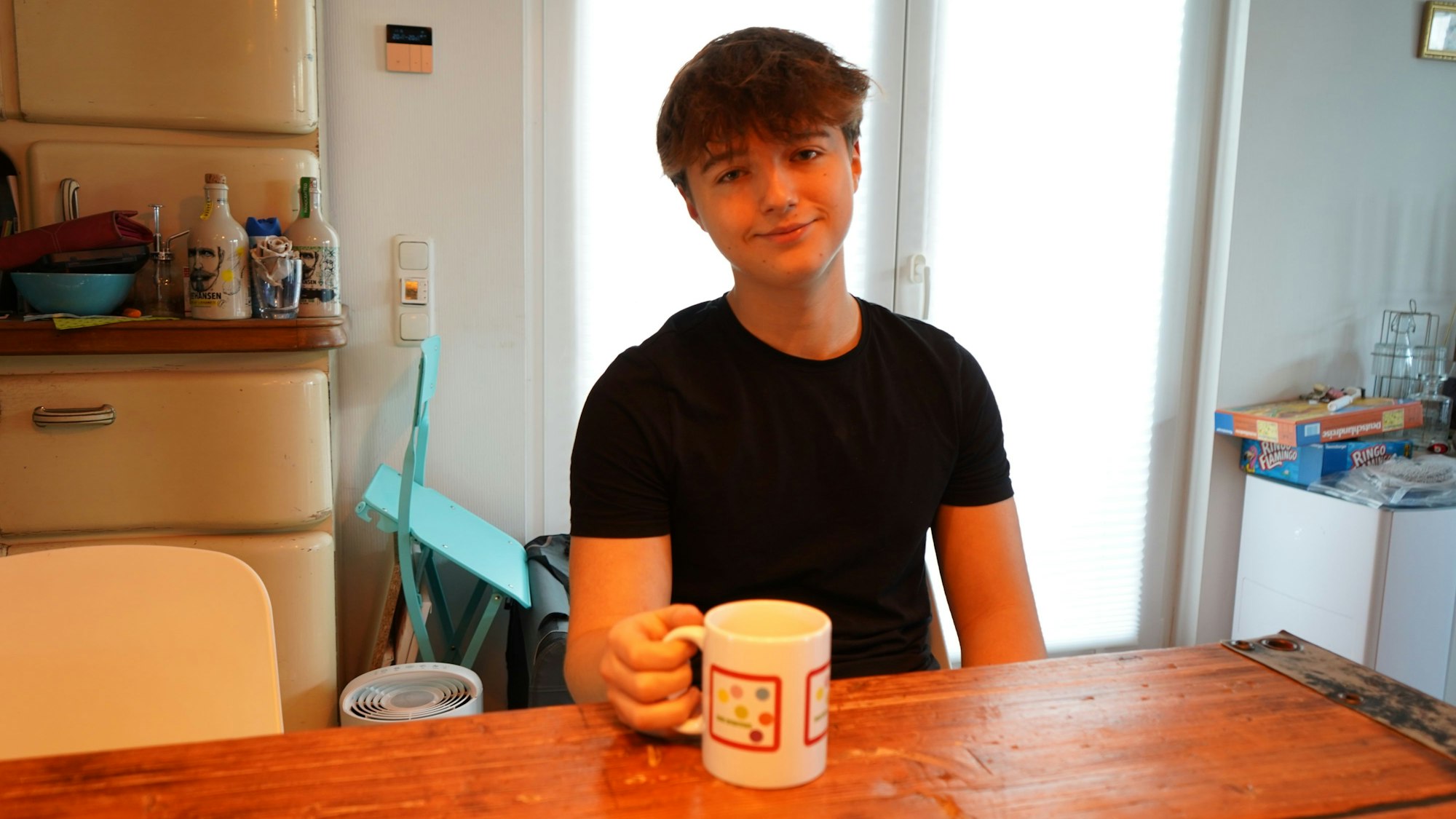 Das Foto zeigt einen Jugendlichen mit einer Tasse in der Hand.