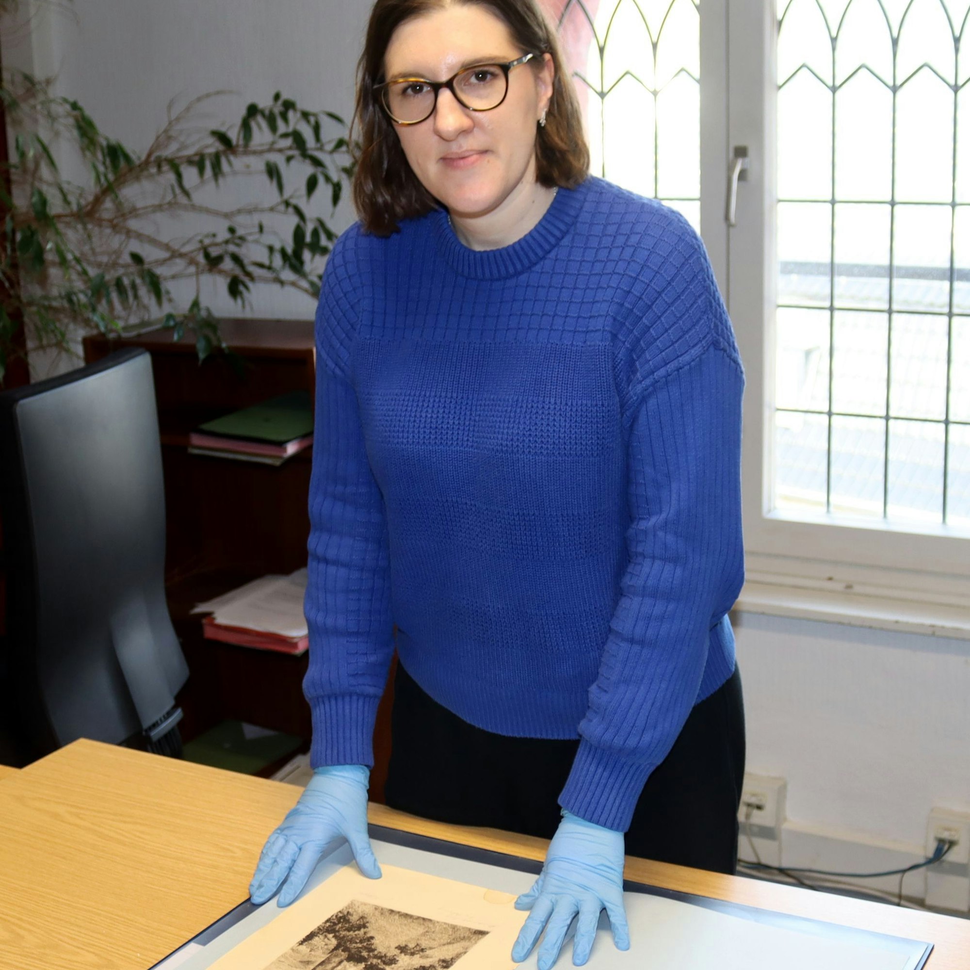 Anna Rosemann begutachtet ein historisches Bild.