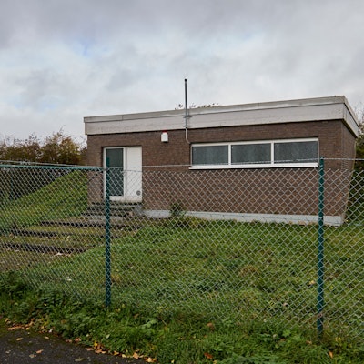 Aufnahme des Hochbehälters in Tondorf: Das unscheinbare Gebäude in Kastenform steht auf einem Hügel hinter einem Zaun.