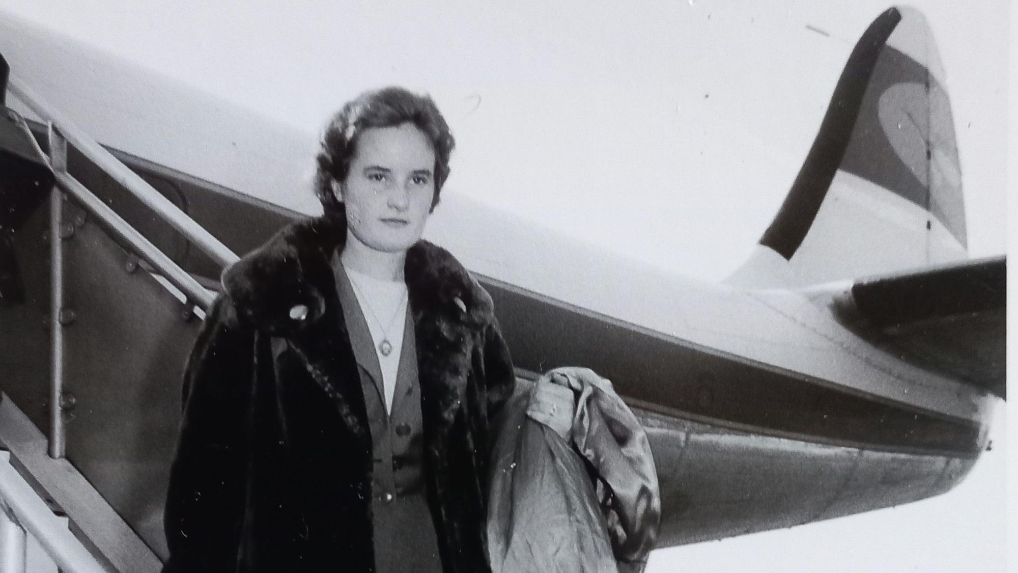 Eine junge Frau steigt in den 1950er Jahren aus einem Flugzeug.