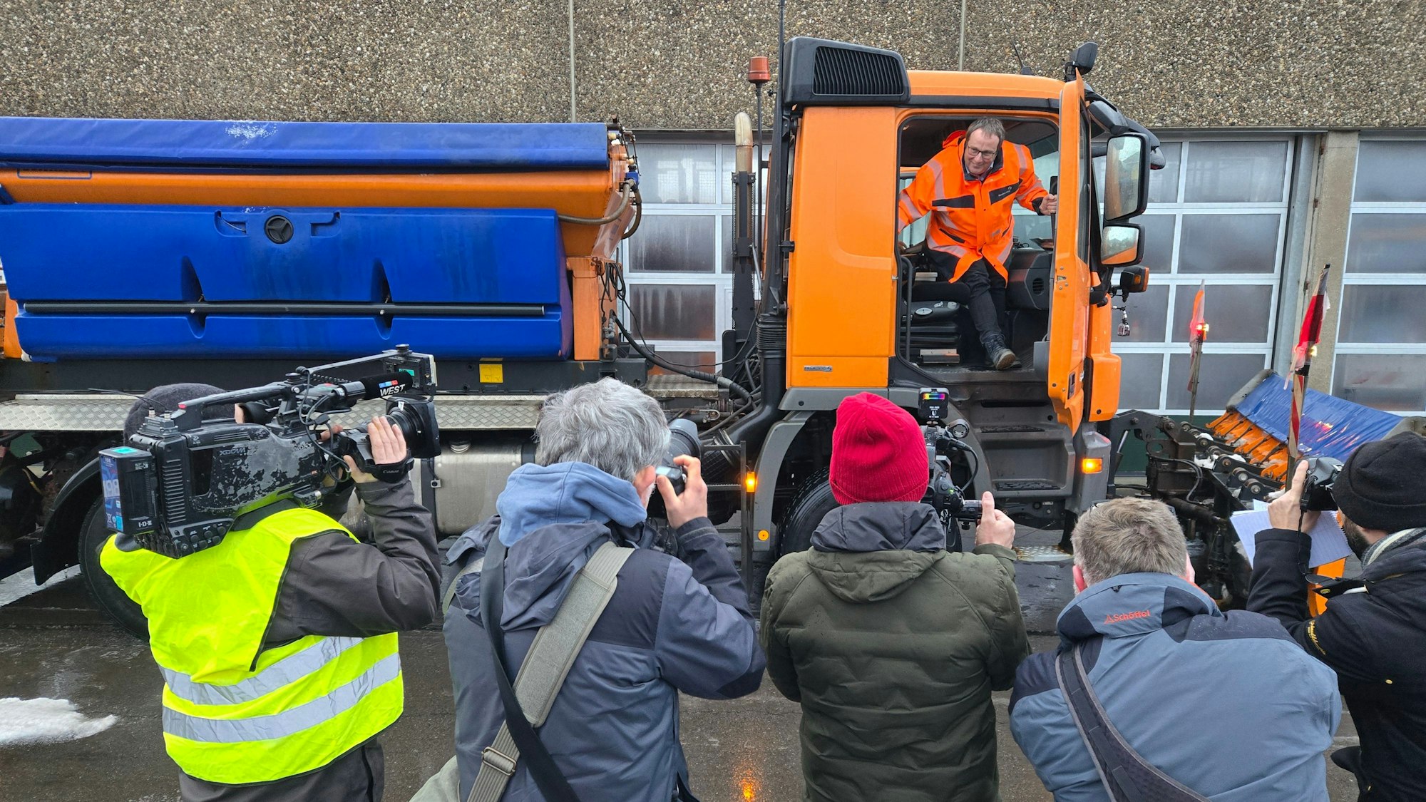 Ein Mann steigt aus einem Lkw und wird dabei von Kameraleuten und Fotografen aufgenommen.