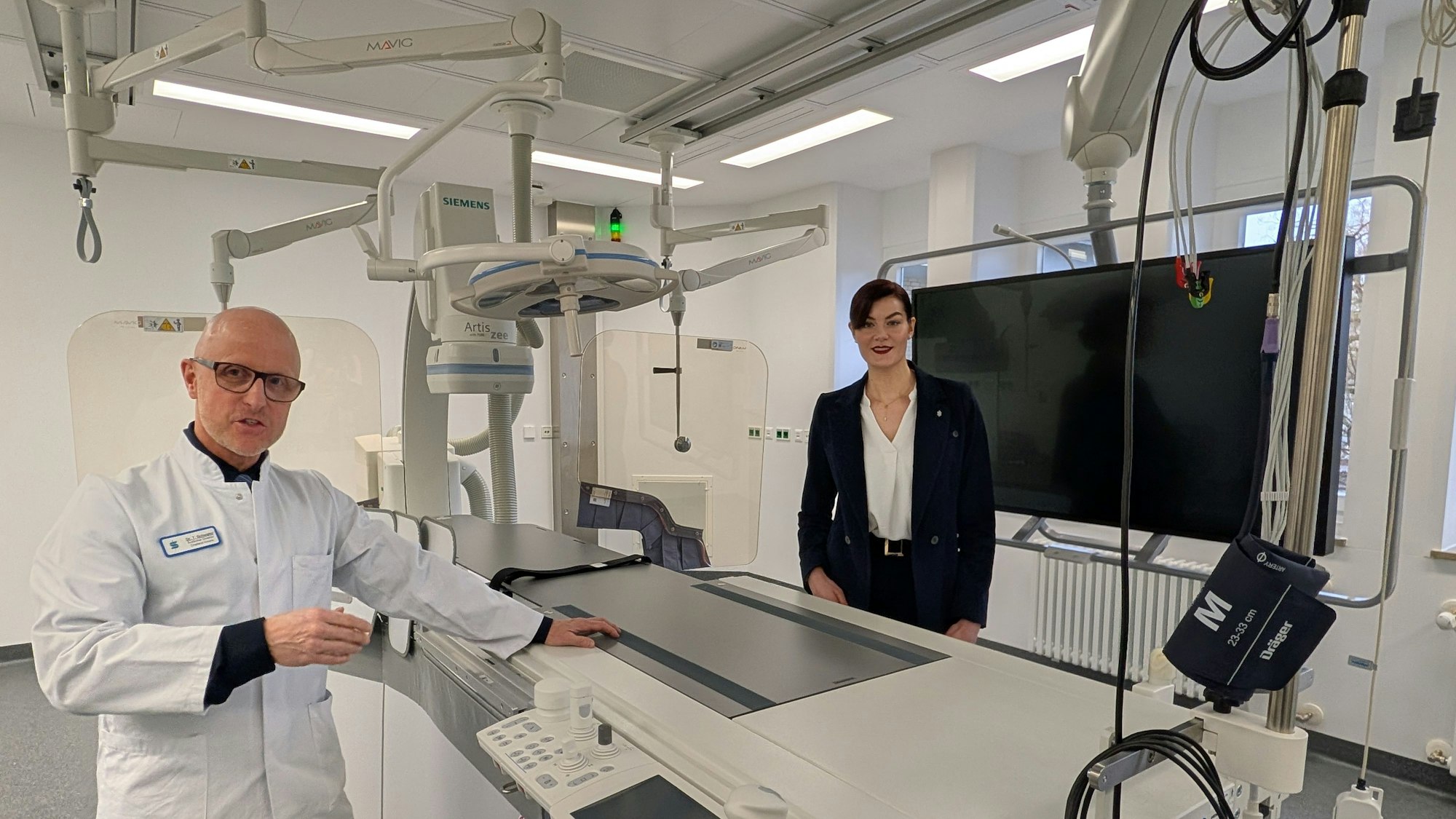 Das Foto zeigt den Chefarzt und die Geschäftsführerin im neuen Herzkatheterlabor.