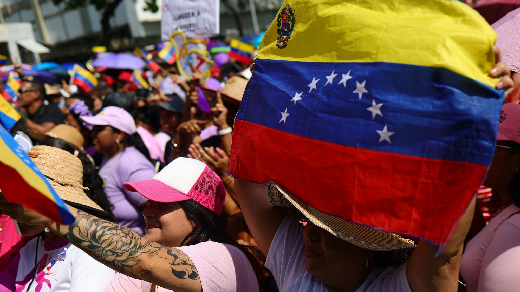 Das Bild zeigt eine Frau, die eine venezolanische Flagge während einer von der Regierungspartei organisierten Kundgebung zur Unterstützung von Präsident Nicolas Maduro und seiner Frau Cilia Flores hält.