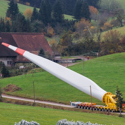 Ein Flügel eines Windrads ist auf einem sogenannten Selbstfahrer montiert und wird durch den Ort Prinzbach transportiert.
