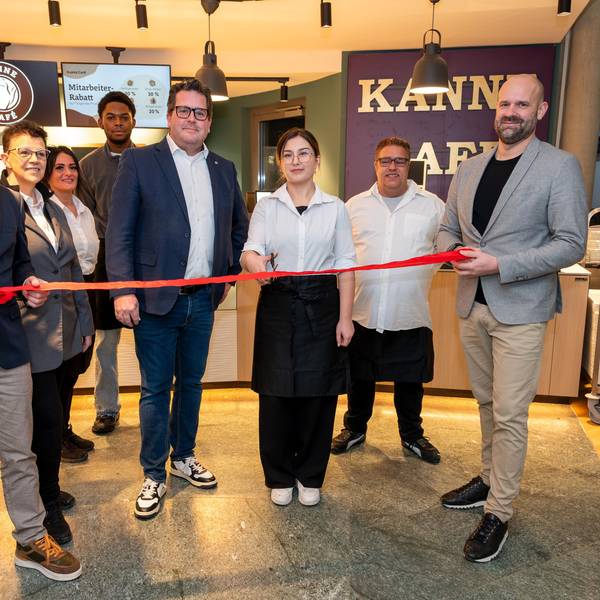 Sebastian Haeger (Geschäftsführer Gesundheitscampus Quirlsberg), der Area Manager von Kanne Café Andreas Brachem und das Team des Cafés schneiden zur Eröffnung im EVK ein rotes Band durch.
