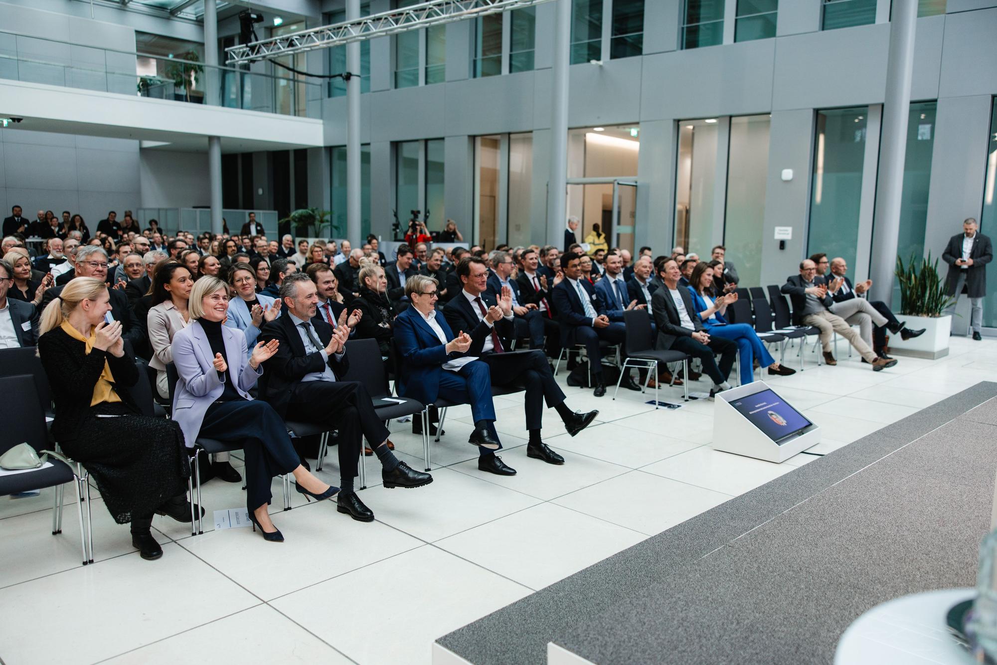 Foyer der NRW Bank mit voll besetzten Besucherreihen.