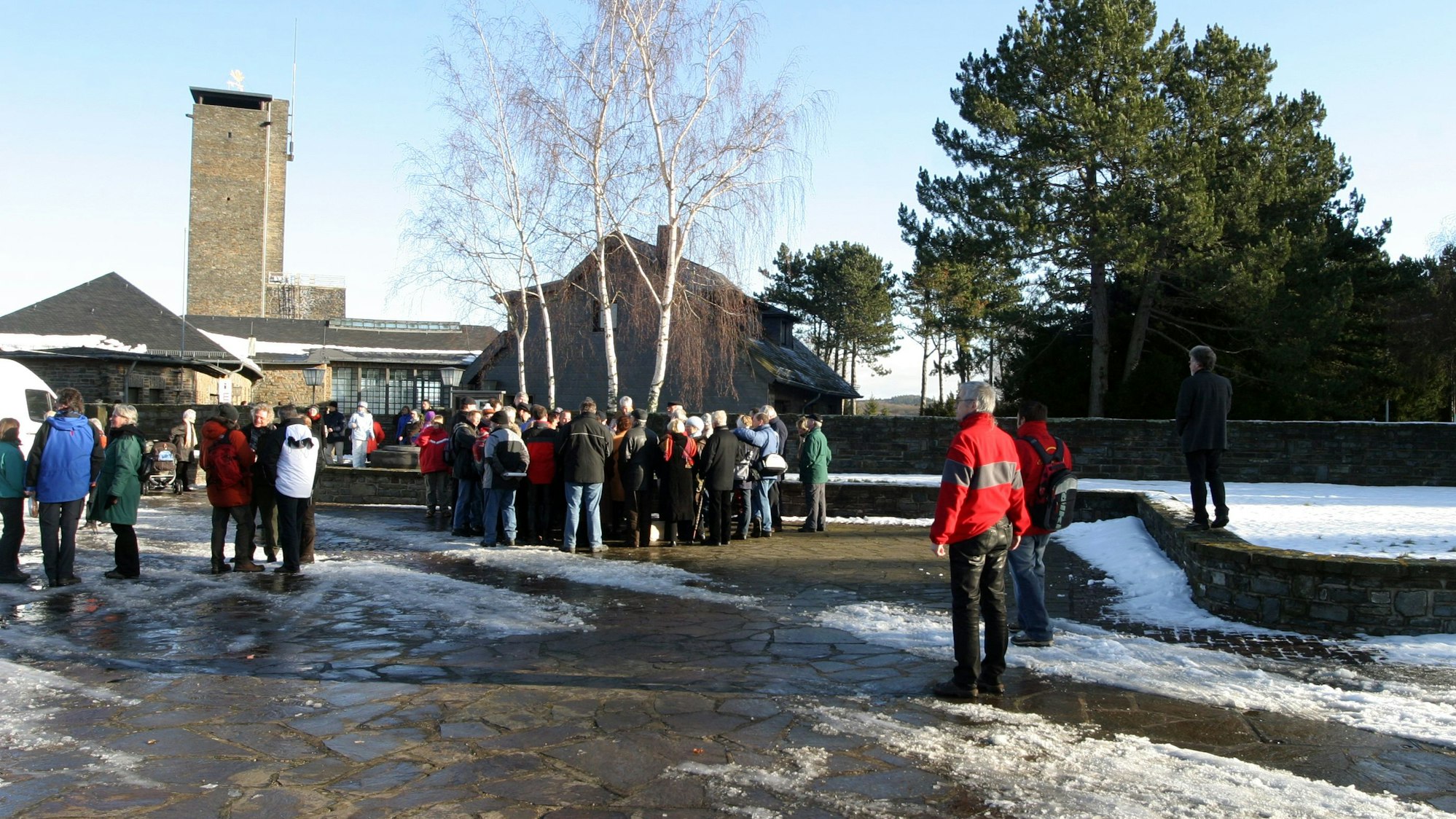 Viele Besucher stehen vor der Kulisse von Vogelsang, es liegt ein Rest Schnee.