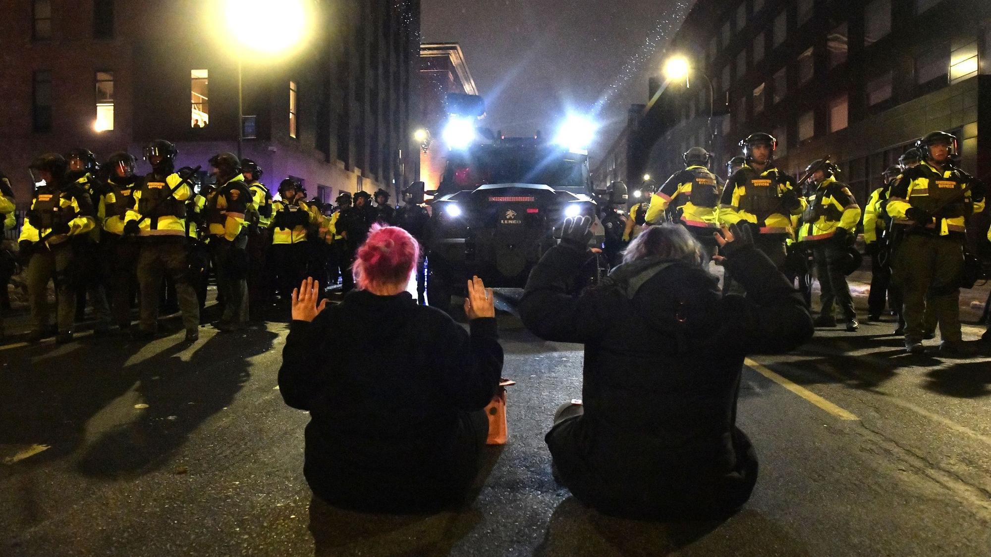 Zwei Demonstranten setzten sich in der Innenstadt von Minneapolis auf die Straße, nachdem sie sich weigerten, den Aufforderungen der Polizei und lokaler Behörden zu folgen, sich nach Protesten gegen die tödlichen ICE-Schüsse auf Renee Nicole Good zu zerstreuen. Die Aktion ist Teil anhaltender Proteste gegen den Einsatz und die tödliche Schussabgabe durch einen Agenten.