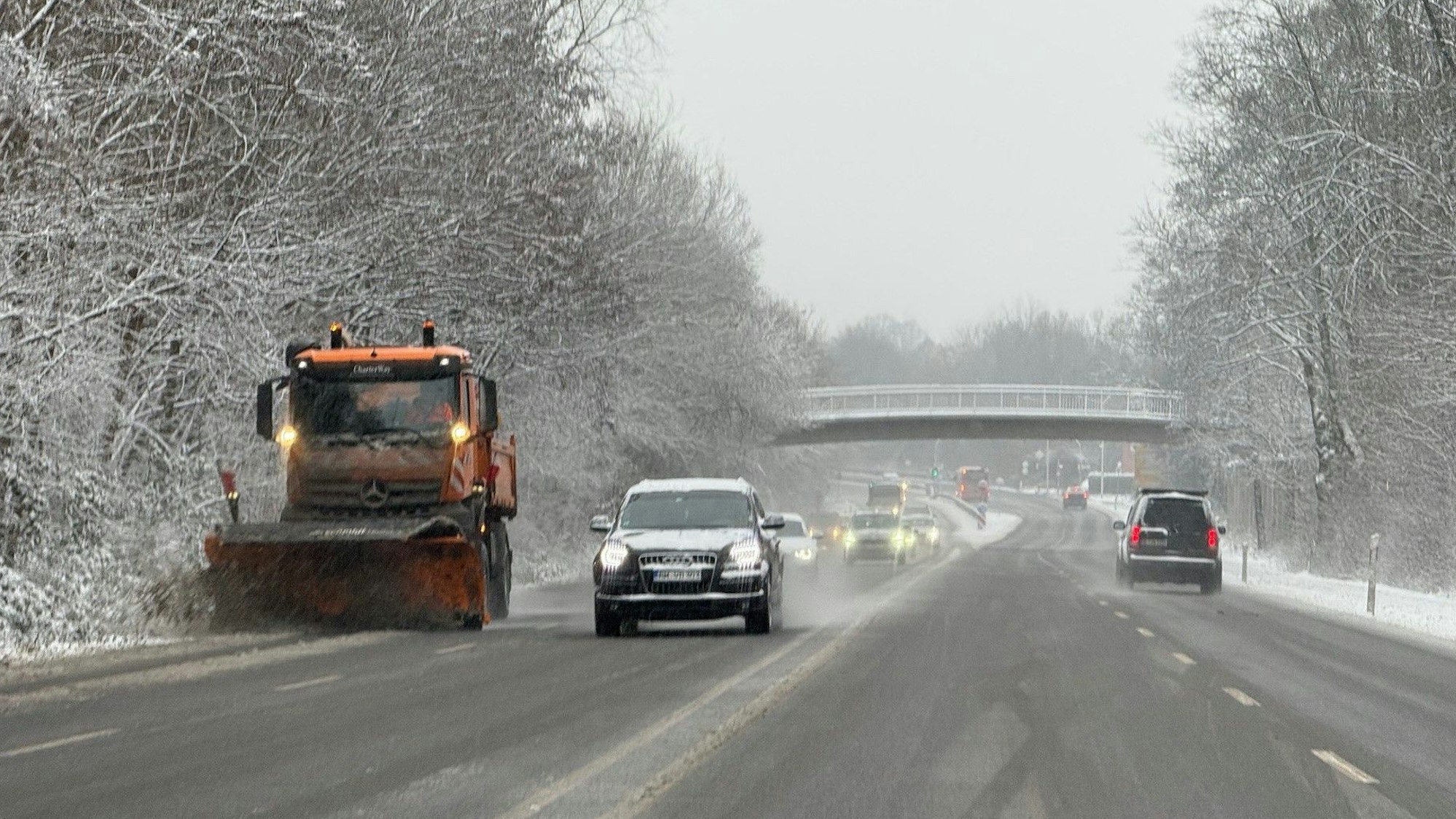 Zu sehen ist ein Schneepflug im Einsatz auf einer Straße.